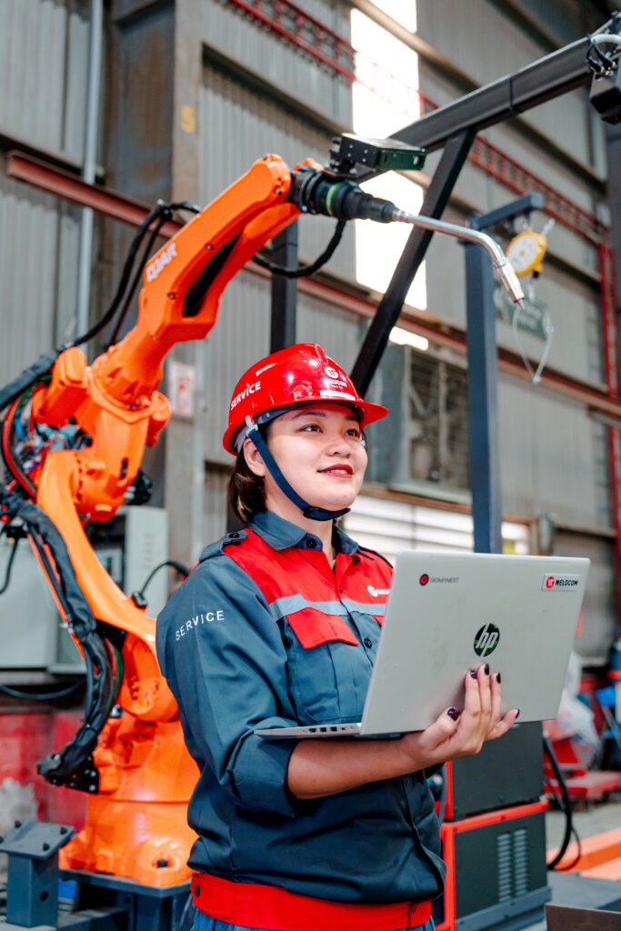 Woman holding laptop performing visual inspection in a factory setting