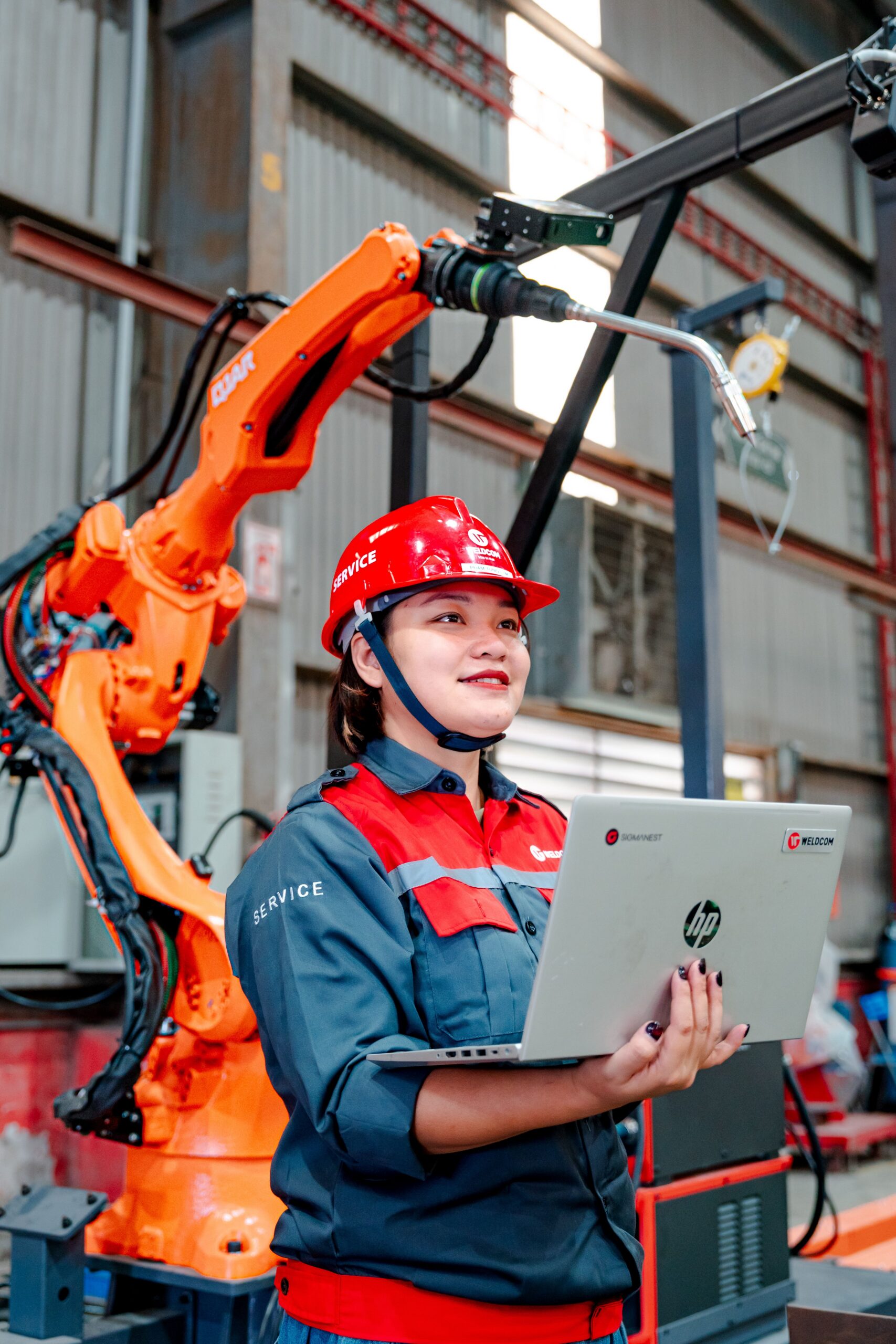 Woman holding laptop performing visual inspection in a factory setting